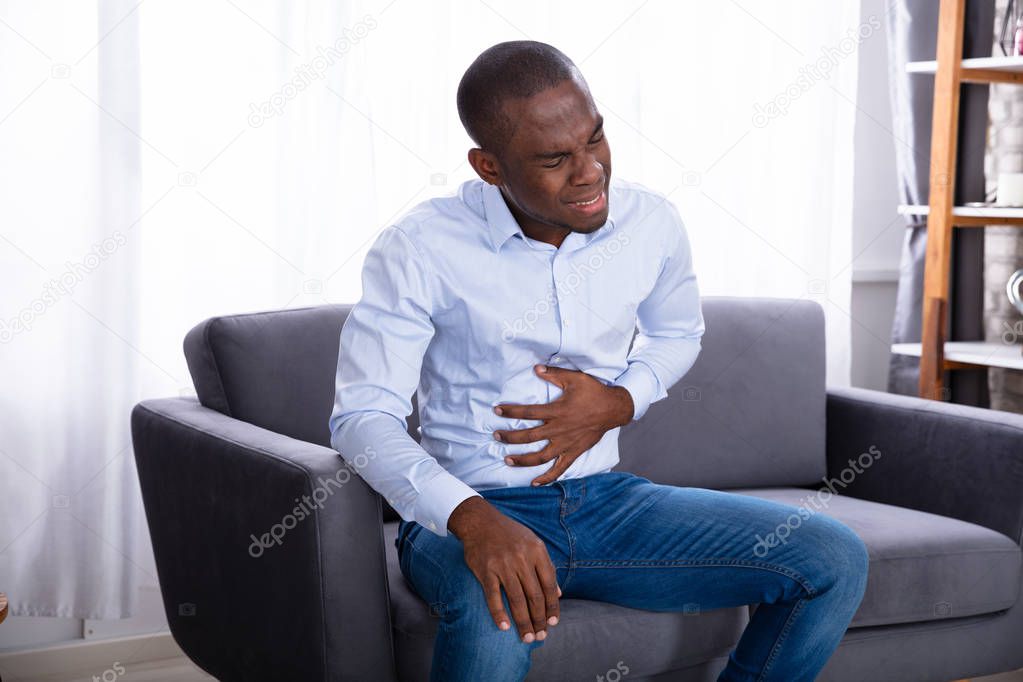 Close-up Of A Young African Man In Pain Holding His Stomach
