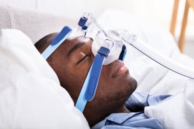 Yatakta uyuyan Cpap maske takıyor bir Afrika gencin yüksek açılı görünüş