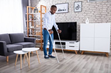 Koltuk değneği katta yürüyüş için kullanan engelli adam