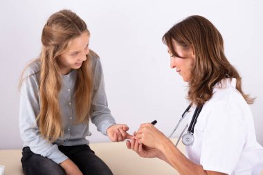 Erkek doktor gülümseyen kız hastanın kan şekeri düzeyini Şeker Ölçüm Kliniği ile kontrol