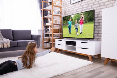 Kız evde televizyon izlerken halı üzerinde yalan