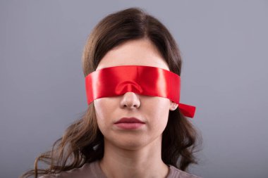 Young Woman's Eye Covered With Red Ribbon On Grey Background clipart