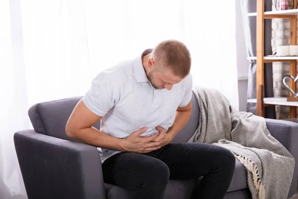 Young Man Sitting Sofa Having Stomach Pain Home — Stock Photo, Image