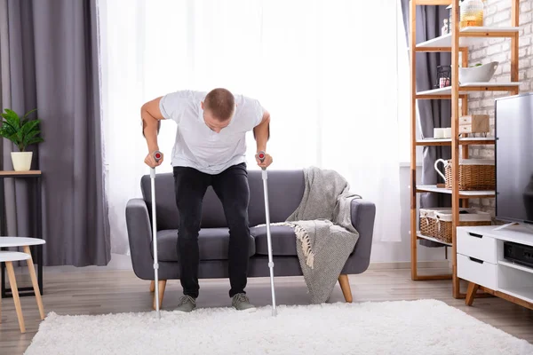 Gehandicapte Jonge Man Met Behulp Van Krukken Staan Van Sofa — Stockfoto