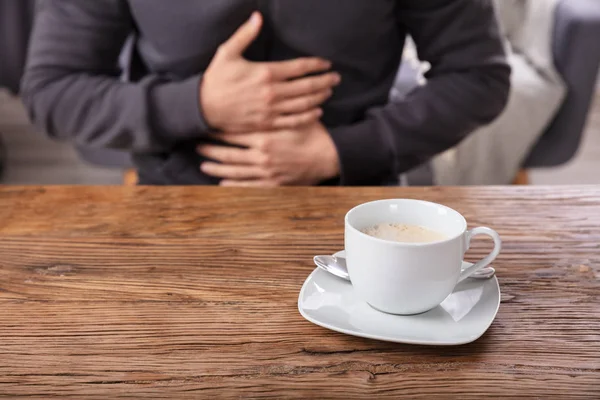 Man Suffering Stomach Pain Cup Coffee Wooden Desk — Stok Foto