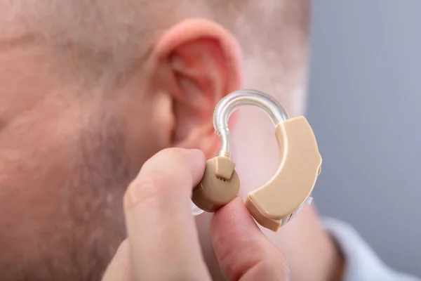 Close Mão Homem Colocando Aparelho Auditivo Seu Ouvido — Fotografia de Stock