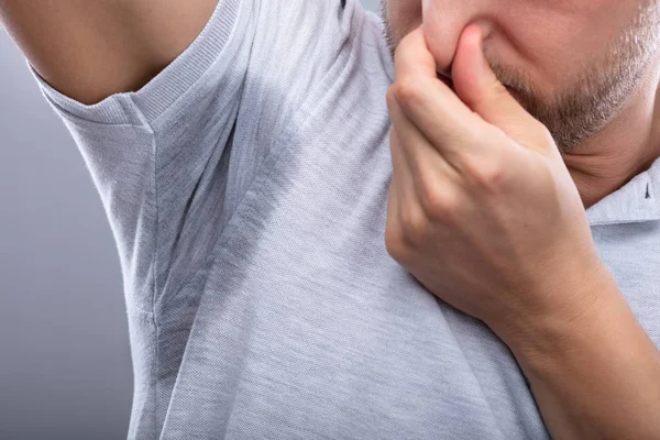 Zbliżenie Mężczyzny Spoconą Pachą Zakrywającą Nos Dłonią — Zdjęcie stockowe
