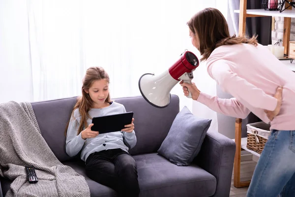 Mother Shouting Megaphone Careless Girl Sitting Sofa Using Digital Tablet — Stock Photo, Image