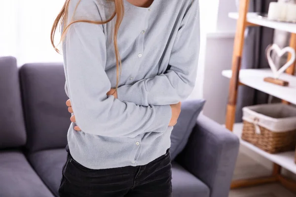 Mädchen Standing Vor Von Sofa Having Magenschmerzen — Stockfoto