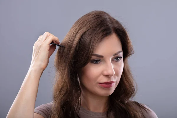 Close Young Woman Combing Her Hair Grey Background — Stock Photo, Image