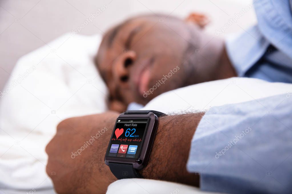 Close-up Of A Man Sleeping With Smart Watch In His Hand Showing Heartbeat Rate