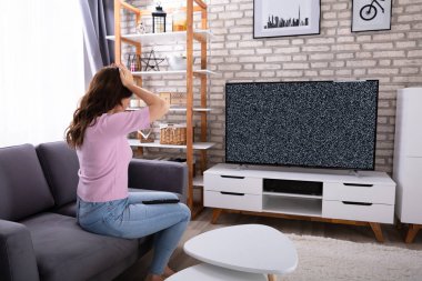 Hayal kırıklığına uğramış genç kadın kanepede televizyon sinyal bakarak oturuyordu