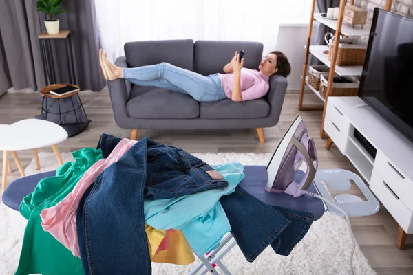 Messy Clothes Iron Ironing Board Front Relaxed Woman Using Smartphone — Stock Photo, Image