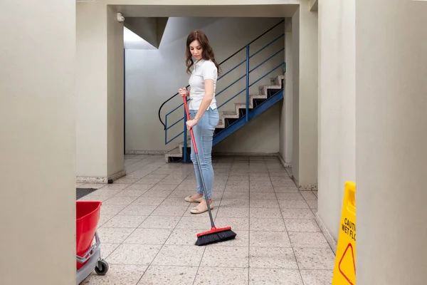 Giovane Donna Janitor Pulizia Pavimento Con Scopa Nel Corridoio — Foto Stock