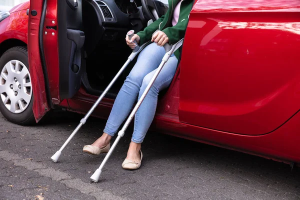 从红色汽车里出来的带着拐杖的残疾妇女 — 图库照片