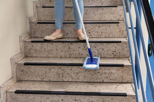 若い女性用務員モップで階段の清掃 — ストック写真