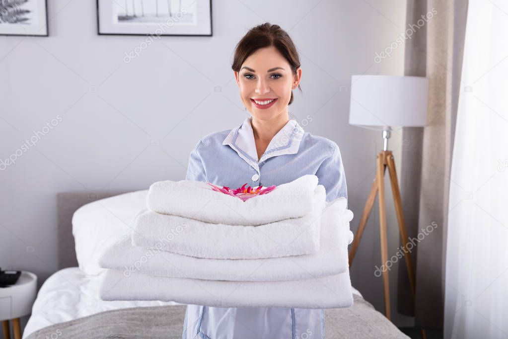 Portrait Of A Happy Young Woman With Stack Of White Towels