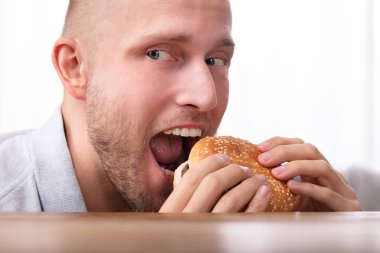 Burger yiyen genç açgözlü bir adam portresi