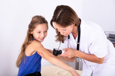 Erkek doktor cilt Dermatoscope Kliniği ile kızın incelenmesi