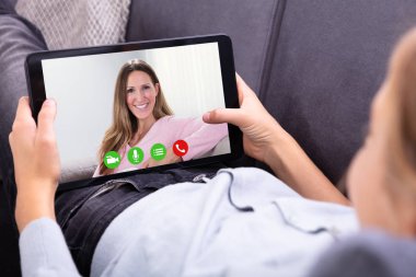 Bir kızın elini Video konferans dijital tablet gülümseyen annesiyle Close-Up