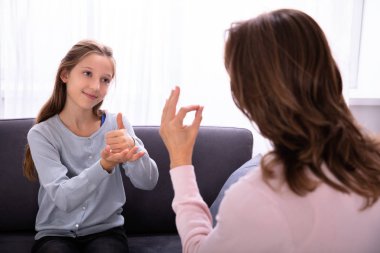 Kadından işaret dilleri öğrenme kanepede oturan mutlu kız