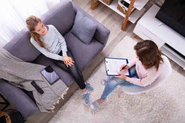Evde kadın psikiyatrist onun sorunları açıklayan kanepede oturan kız