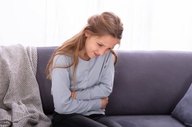Mide ağrısı acı kanepede oturan kız
