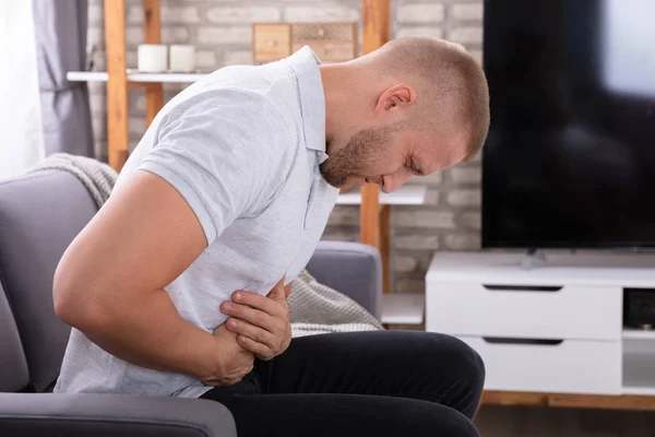 Young Man Sitting Sofa Having Stomach Pain Home — Stock Photo, Image