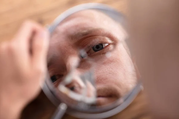 Nahaufnahme Des Gesichts Eines Mannes Zerbrochenem Spiegel Über Holztisch — Stockfoto