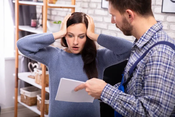 Chockad Kvinna Som Tittar Fakturan Visas Manliga Tekniker — Stockfoto