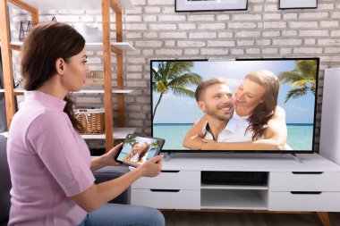 Genç bir kadın televizyon kanalı aracılığıyla kablosuz dijital tablet bağlanma yan görünüm
