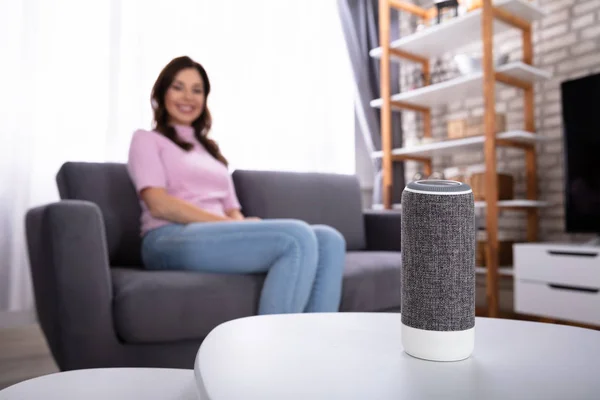 Close-up Of Wireless Speaker Near Woman Sitting On Sofa
