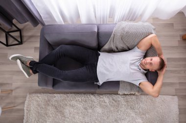 Koltukta oturan genç gülümseyen bir adam yüksek açılı görünüş