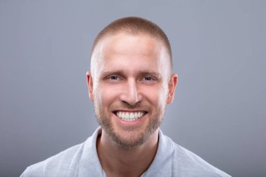 Gri arka plan üzerinde mutlu bir genç adam portresi