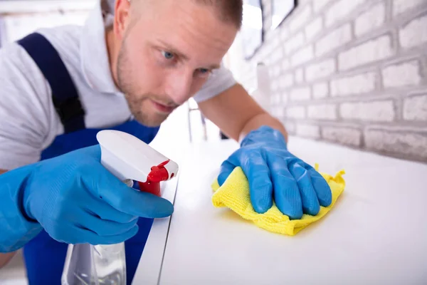 一个年轻的男性门卫清洁家具与黄色布的特写镜头 — 图库照片