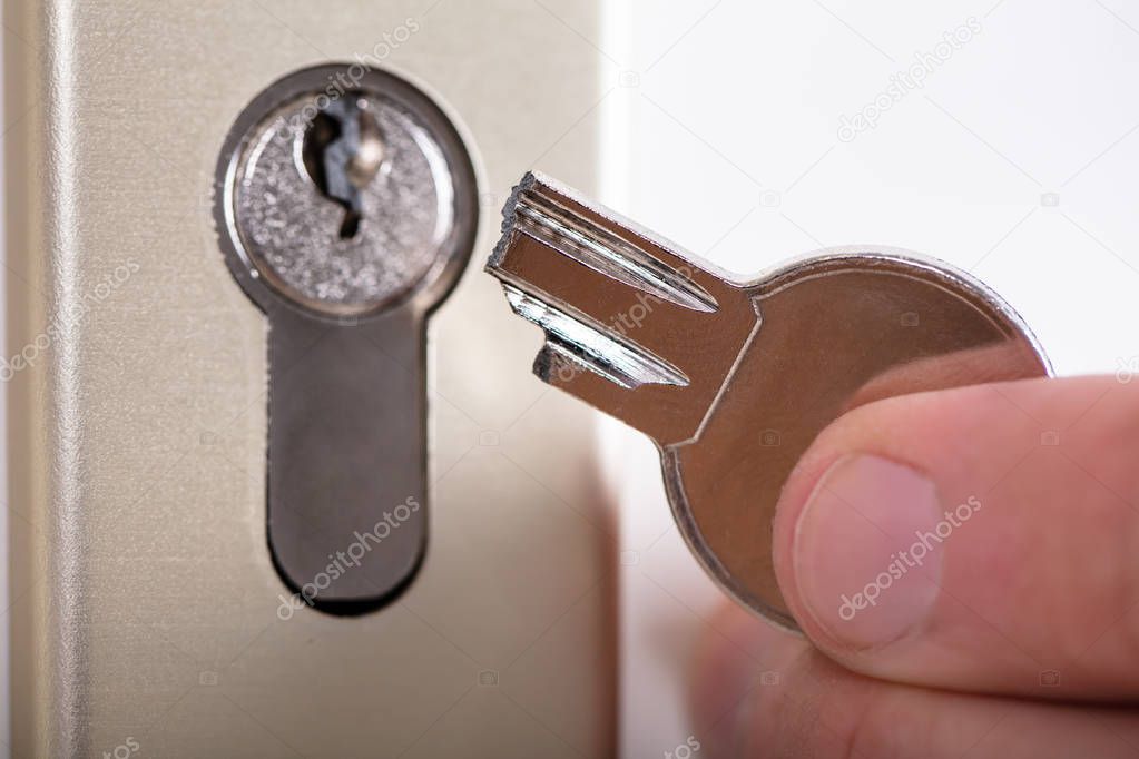 Close-up Of A Man Holding Broken Key Near Keyhole