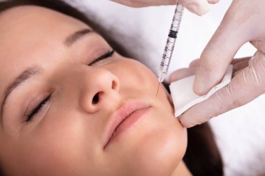 Doktor el enjeksiyon genç kadının yüzünde vererek Close-up