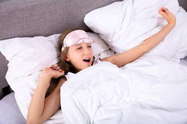 Mutlu bir kızın kollarını uyku modundan çıkarma sonra kadar uzanan yüksek açılı görünüş