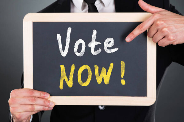 Крупный план руки человека, указывающего на голосование, текст на листе
