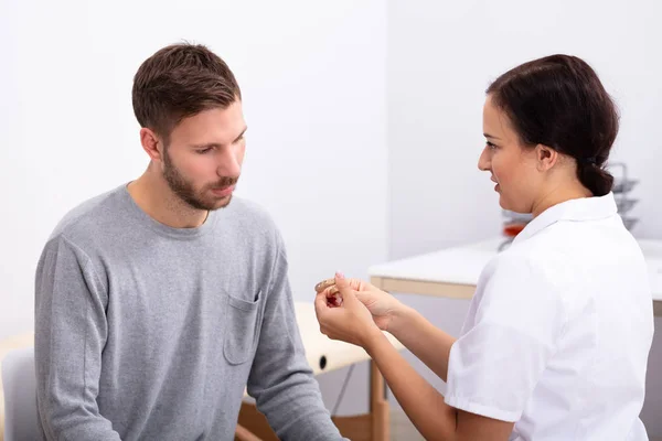 Ung Manlig Patient Tittar Kvinnliga Läkare Som Håller Hörapparat Kliniken — Stockfoto