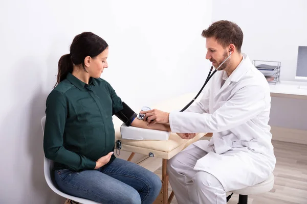 Joven Médico Masculino Revisando Presión Arterial Sonriente Paciente Femenina Clínica —  Fotos de Stock