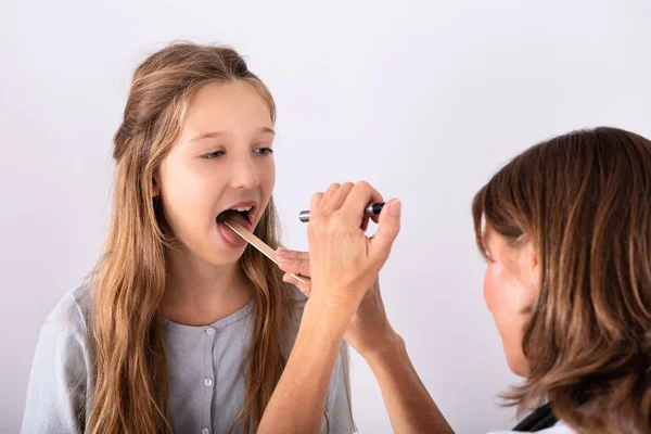 女の子の舌圧子と喉の痛みをチェックする医者のクローズ アップ — ストック写真