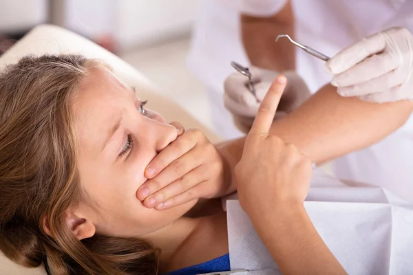 クリニックでの歯科治療を行っている間の手で彼女の口を覆っている怯えた少女 — ストック写真