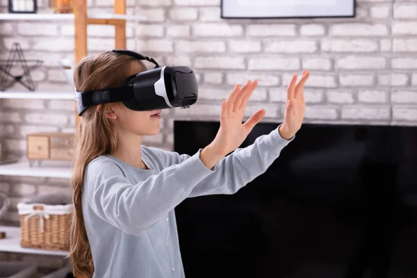 一个女孩在家里使用虚拟现实耳机的侧视图 — 图库照片