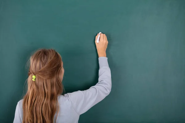 Achteraanzicht Van Een Vrouwelijke Student Schrijven Met Krijt Groene Schoolbord — Stockfoto