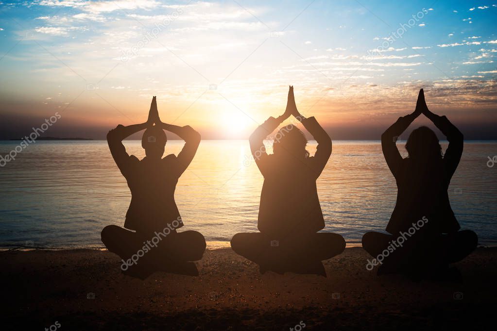 Silhouette Of People Meditating At Beach During Sunset