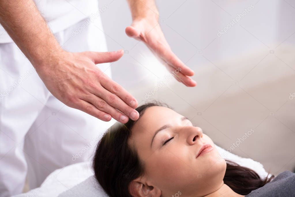 Close-up Of A Therapist Hand Giving Reiki Healing Treatment To Woman In Spa