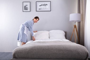 Gülümseyen kadın kahya otel odasında yatak yapma