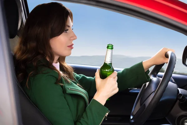 車を運転中にビール瓶を保持している美しい若い女性の側面図 — ストック写真