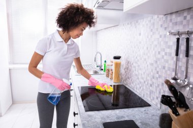 Sünger ve mutfak sprey deterjan ile genç bir kadın indüksiyon temizlik Close-up soba